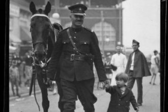 A mounted police officer helps a lost child find her parents at the CNE in 1929.