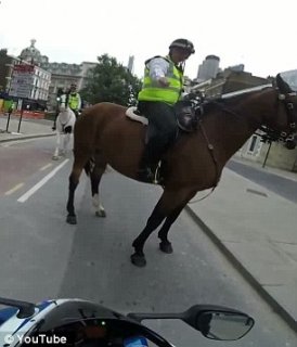 Stern warning: The driver is given a talking-to by the two mounted policemen